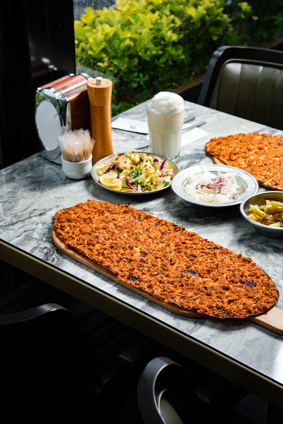 Mermer masada tahta tepside kürek lahmacun, yanında piyaz, sarımsaklı yoğurt ve ayran